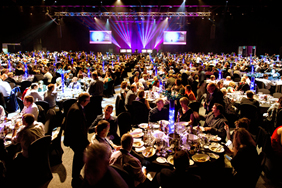 A photo of a big venue full of people sitting around tables and dining.
