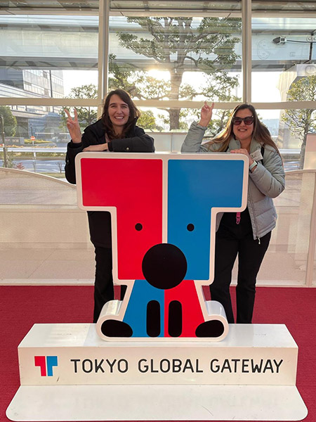 Photo of 2 teachers with the Tokyo Global Gateway sign stand.